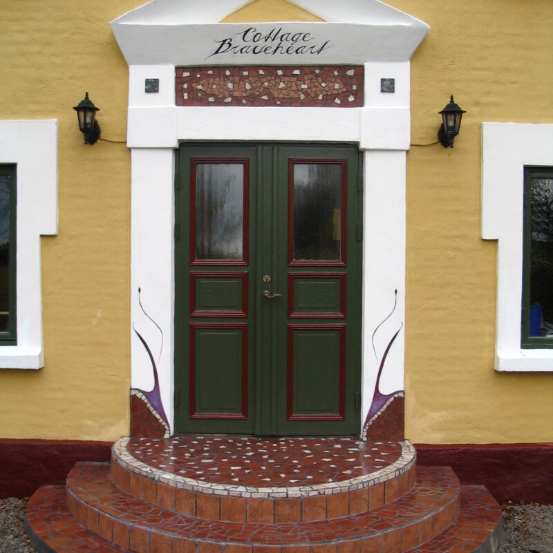 Tiles on doorstep and wall and painted decoration on a door entrance of a house in Bara, Sweden